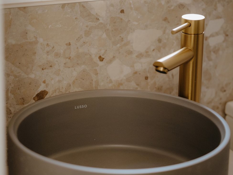 A sink with a gold faucet in a bathroom at Baldslow Stables in Battle near Hastings