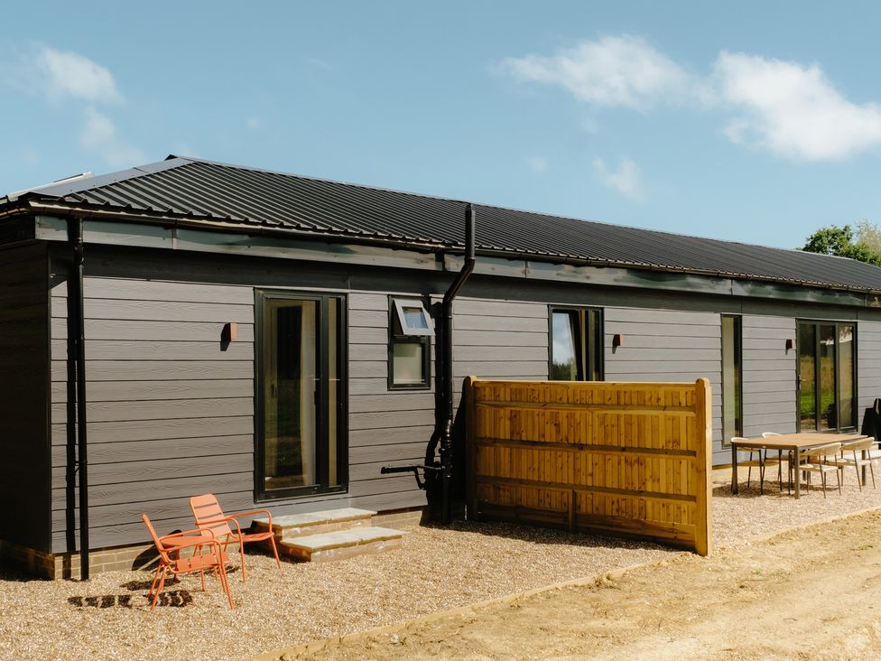 An outdoor view of a house with a fence and chairs at Baldslow Stables Battle near Hastings
