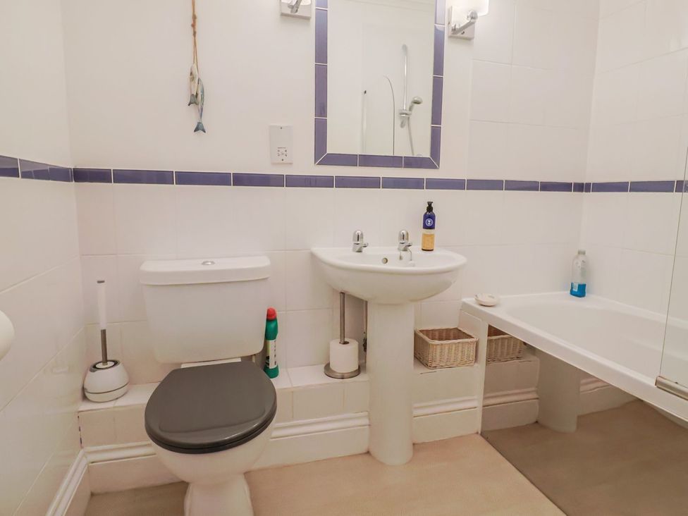 A bathroom with a toilet, sink, mirror, and bathtub at 2 St. Michaels House Lyme Regis