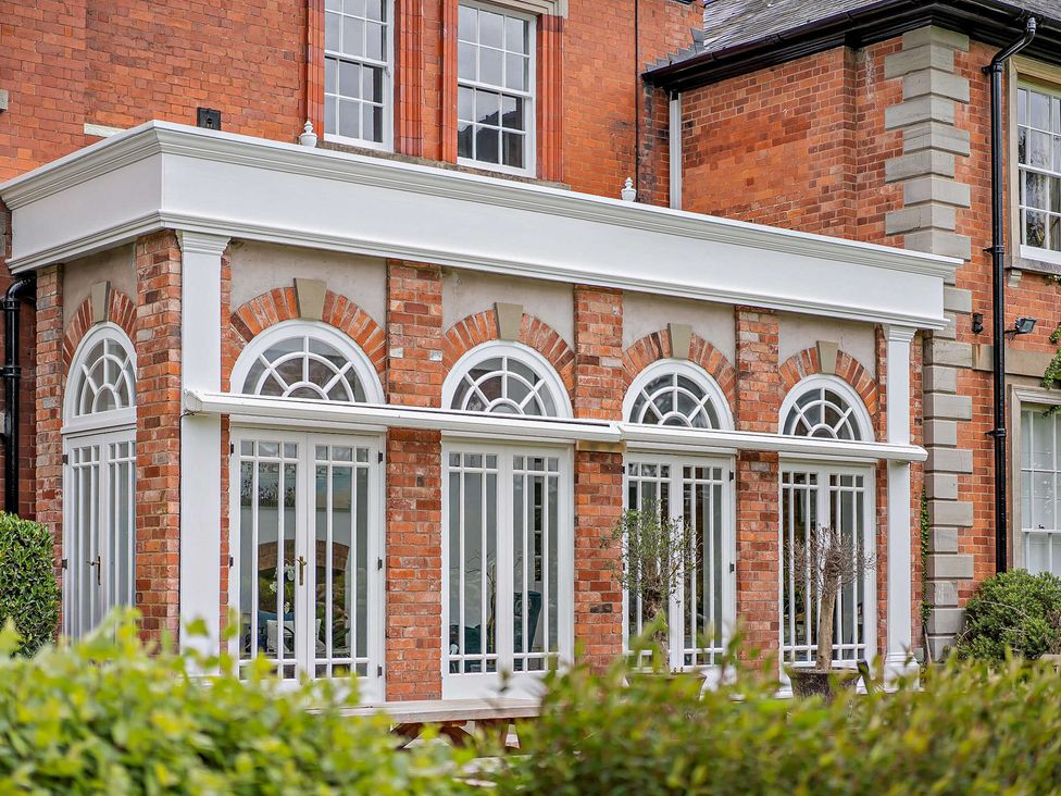 A conservatory with glass windows and brick walls at Gate House Leominster