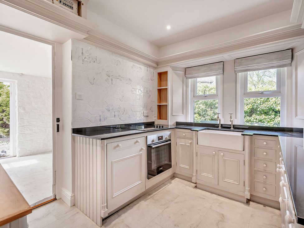 A kitchen with cabinets, sink, and windows at Gate House in Leominster