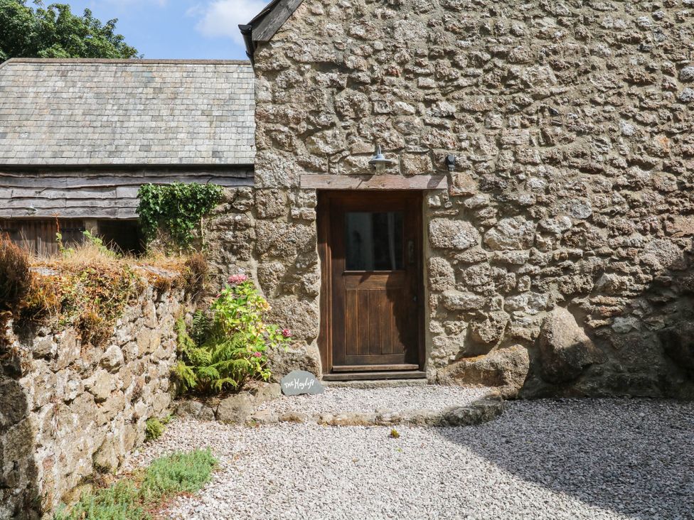 An entrance with a wooden door and stone wall at The Hayloft at Manaton