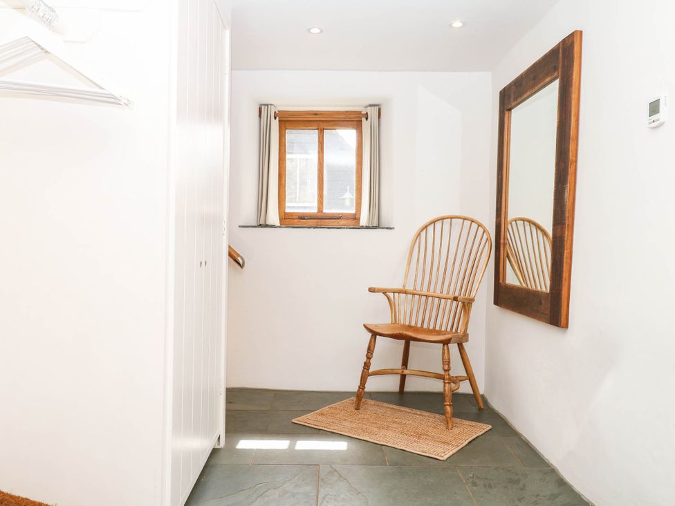 An entryway with a chair and mirror at The Hayloft at Manaton