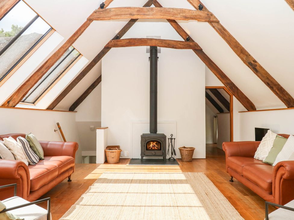 A living room with sofas and a stove at The Hayloft at Manaton