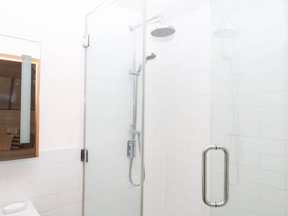A shower with glass panels and a shower head at The Hayloft at Manaton