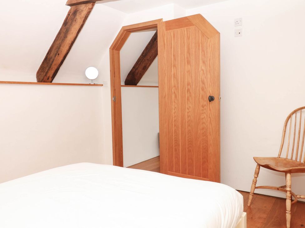 A bedroom with a bed and a chair at The Hayloft at Manaton