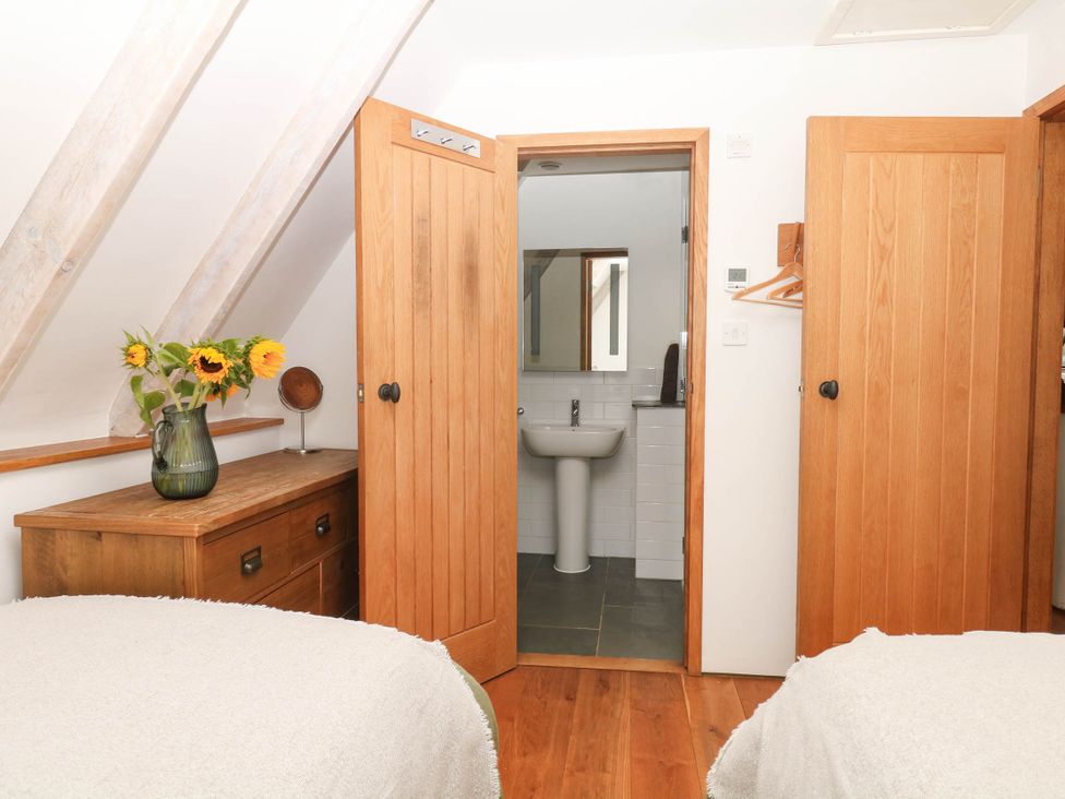 A bedroom with two beds and an adjoining bathroom at The Hayloft at Manaton