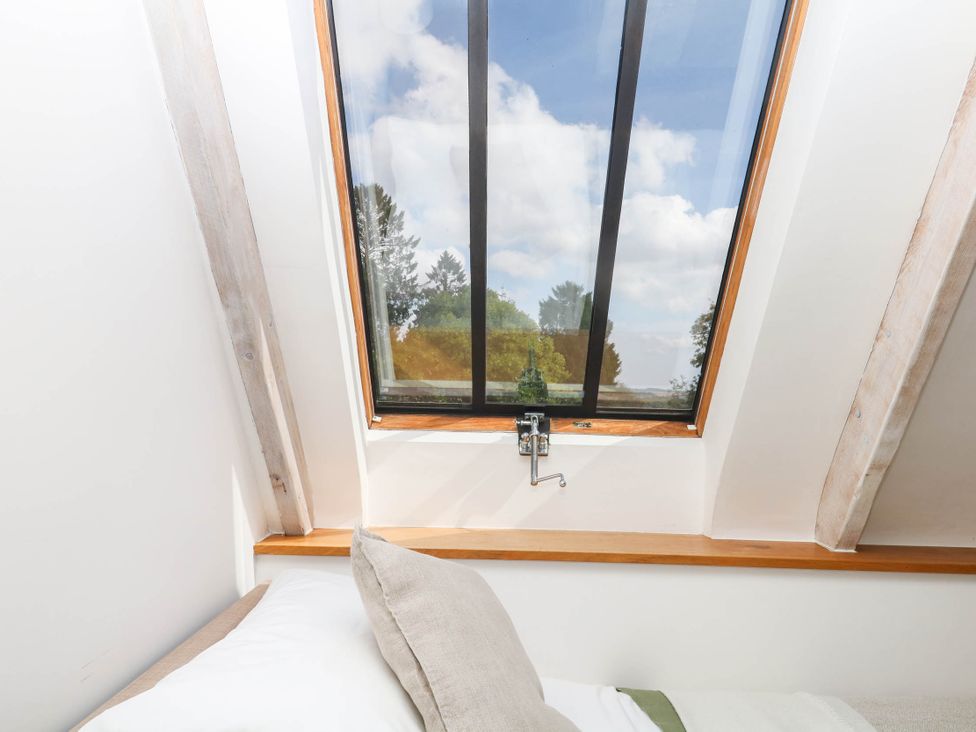 A bedroom with a window showing trees at The Hayloft at Manaton