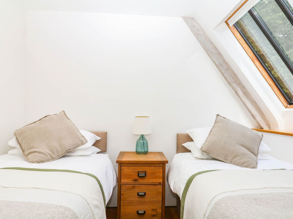 A bedroom with two beds and a bedside table at The Hayloft at Manaton