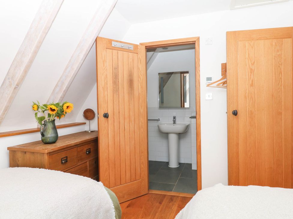 A bedroom with a sink and mirror visible through an open door at The Hayloft at Manaton