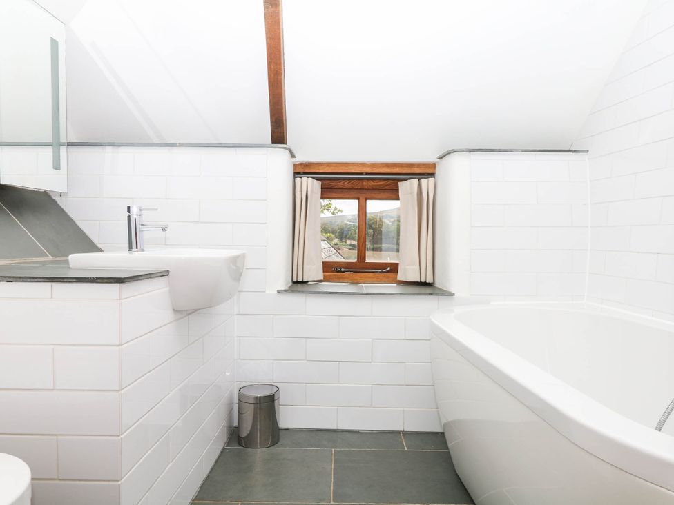 A bathroom with a bathtub and sink at The Hayloft at Manaton