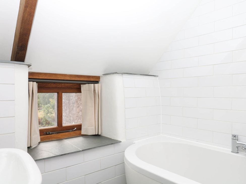 A bathroom with a bathtub and a window at The Hayloft at Manaton