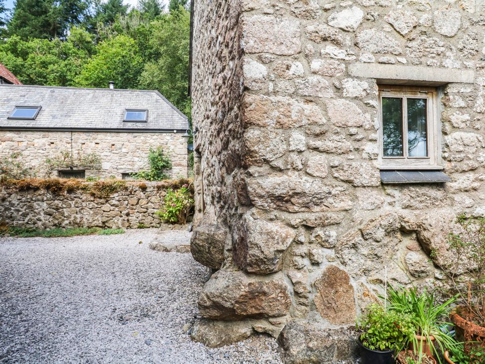 A stone wall with a window and gravel path outside The Hayloft at Manaton