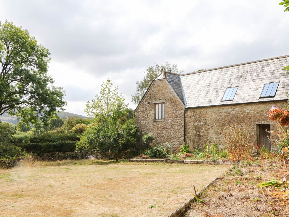 An outdoor view of a stone building with a grassy area at The Hayloft at Manaton
