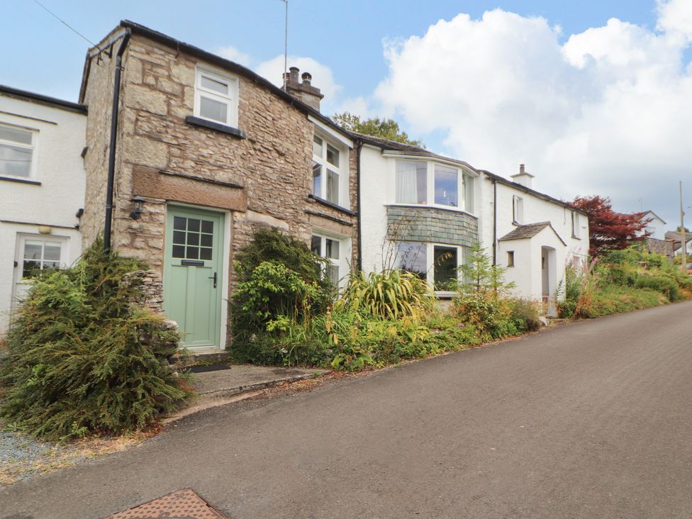 A house with a green door and plants on the side at The Orchard in Levens