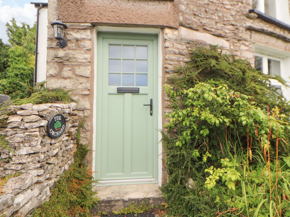 A green door with a stone wall and plants at The Orchard in Levens