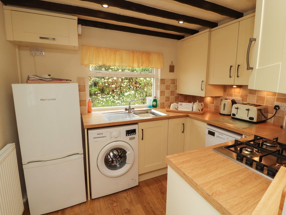A kitchen with a refrigerator, washing machine, and gas stove at The Orchard in Levens
