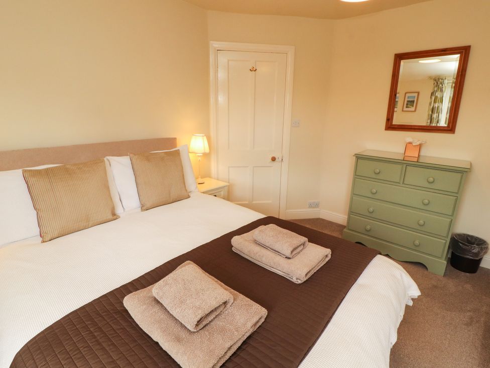 A bedroom with a bed, dresser, and lamp at The Orchard in Levens
