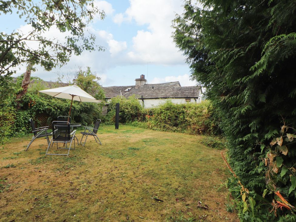 A garden with chairs and an umbrella at The Orchard in Levens
