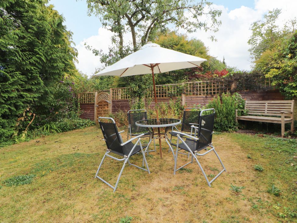 A garden with a table and chairs under an umbrella at The Orchard in Levens
