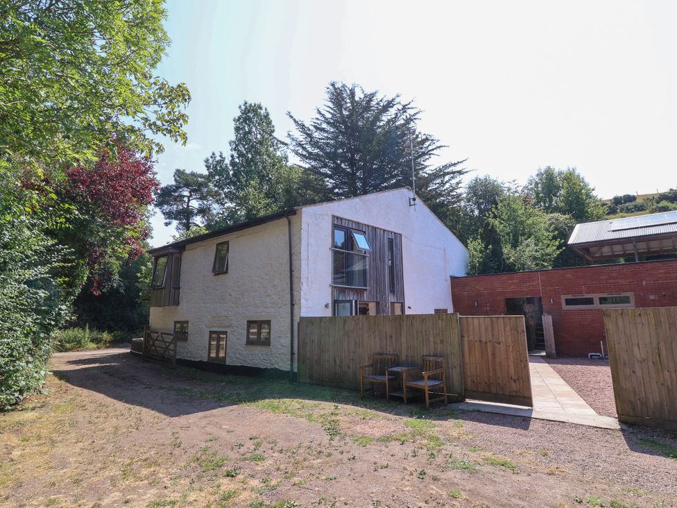 A house with a patio area and trees at Down Cottage in Zeal Monachorum