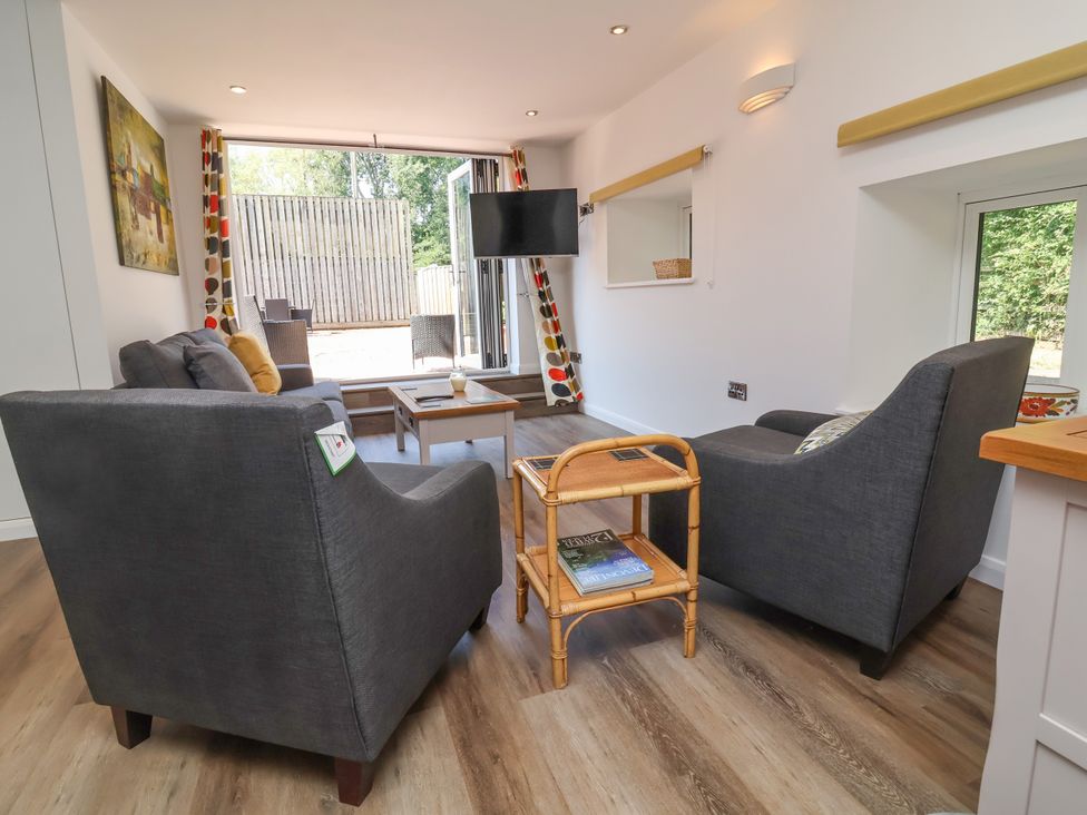 A living room with a sofa, armchairs, and a coffee table at Down Cottage, Zeal Monachorum
