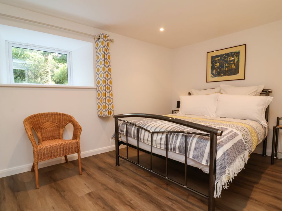 A bedroom with a bed, chair, and window at Down Cottage in Zeal Monachorum