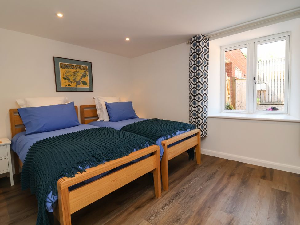 A bedroom with two beds and a window at Down Cottage in Zeal Monachorum
