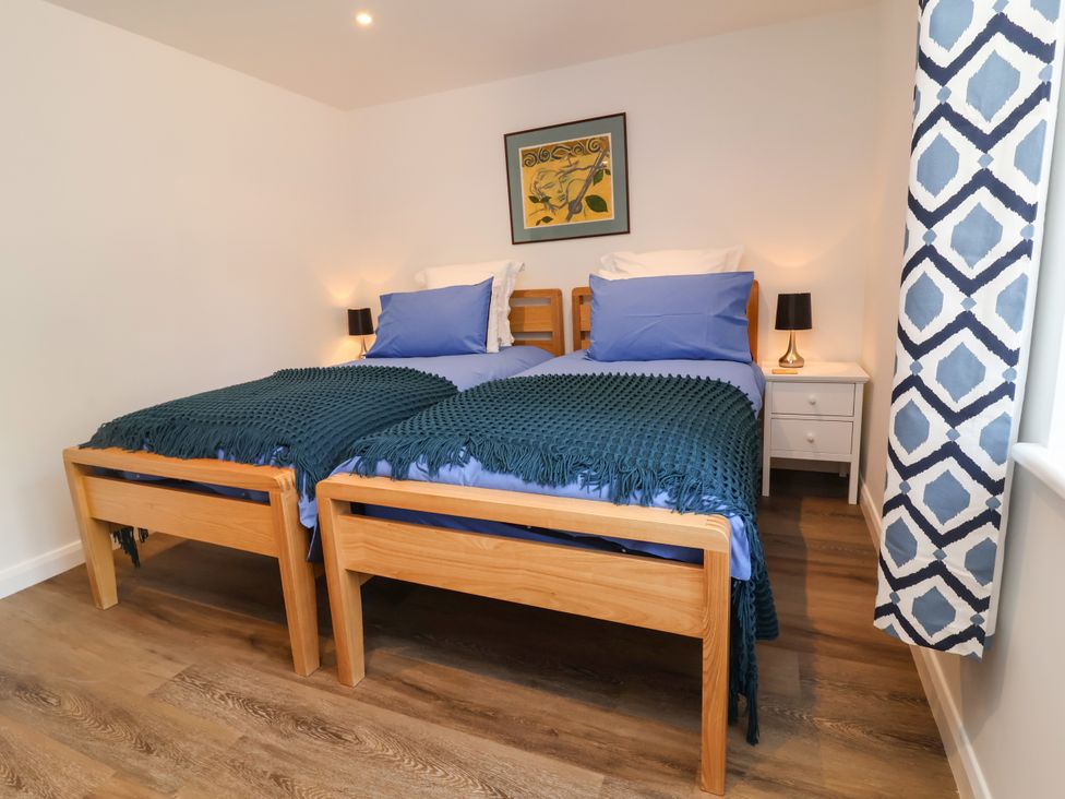 A bedroom with two beds and a bedside table at Down Cottage in Zeal Monachorum