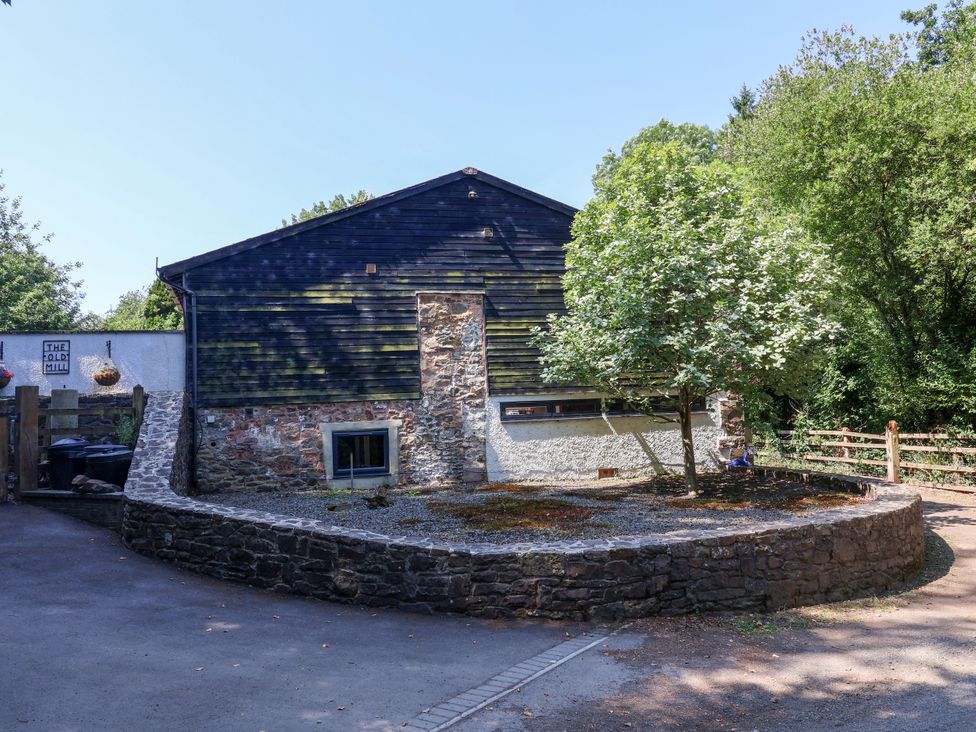 A building with a tree and stone wall at Down Cottage in Zeal Monachorum