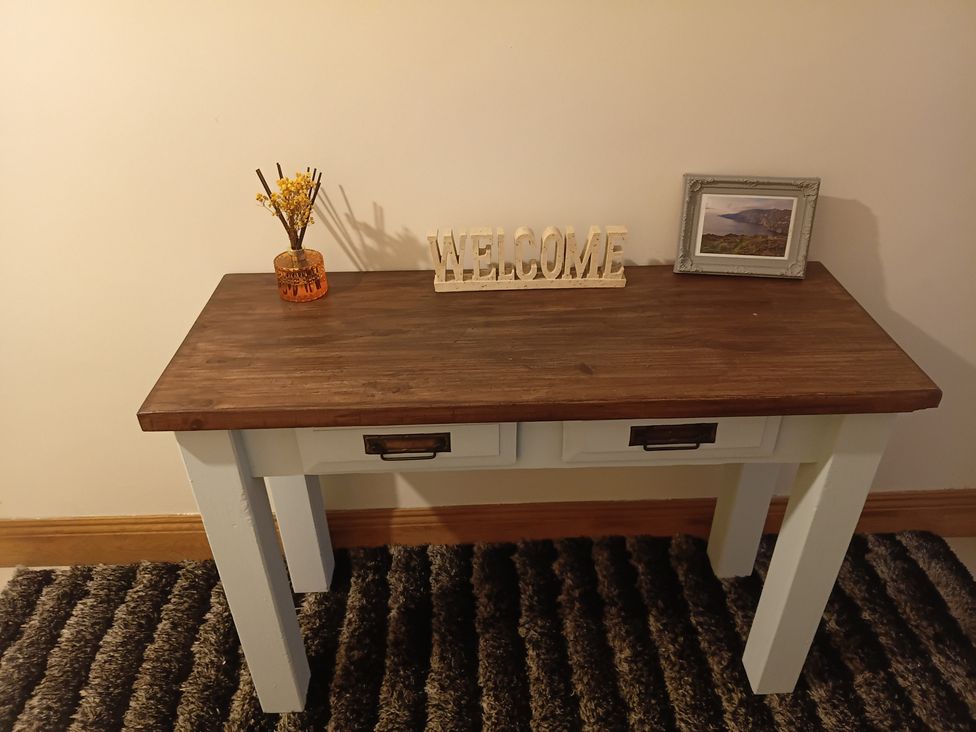 An entryway table with a welcome sign and decorative items at Sliabh League Mountain Lodge in TEILEANN near Kilcar, County Donegal