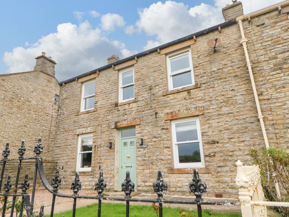 A house exterior with stone walls and a green front door at Hillside House in Leyburn