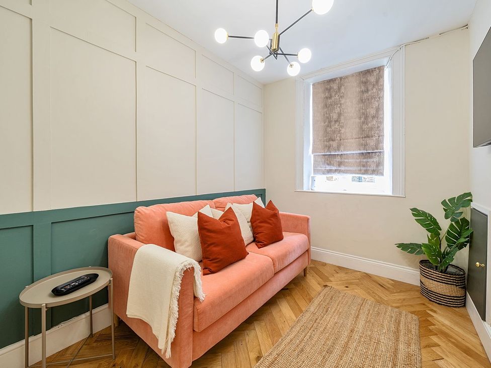 A living room with a coral sofa and a side table at Hillside House in Leyburn
