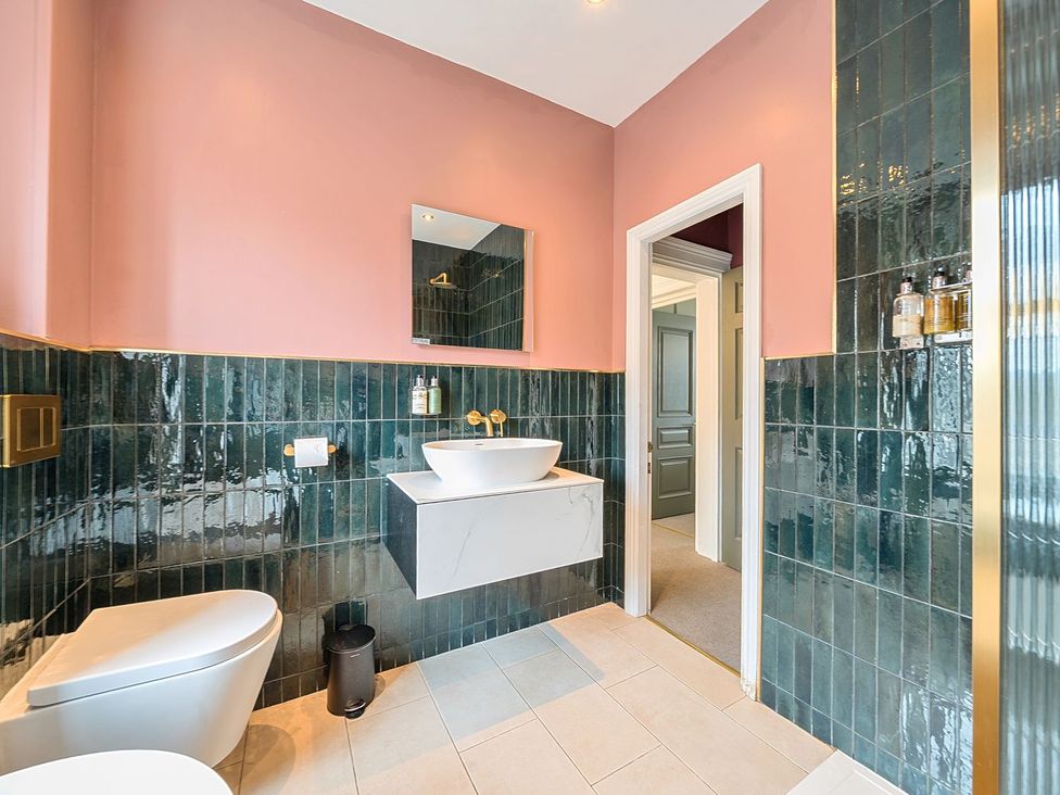 A bathroom with a toilet, sink, and mirror at Hillside House Leyburn