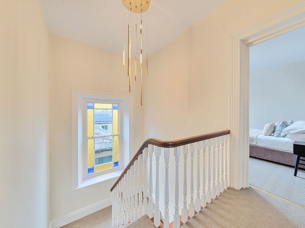 A staircase with a window and chandelier at Hillside House Leyburn