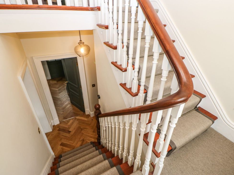A staircase with a railing and light fixture at Hillside House in Leyburn