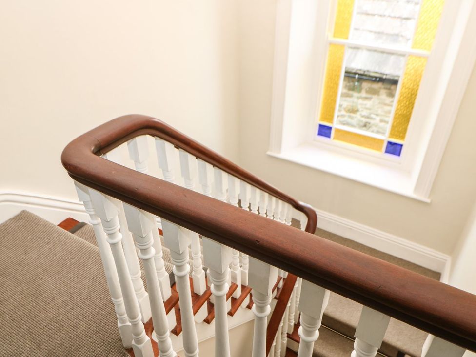 A staircase with a wooden railing and a window at Hillside House in Leyburn