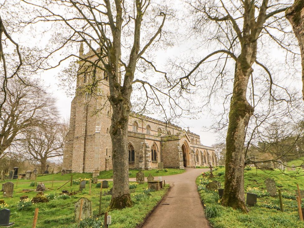 A church surrounded by trees and gravestones at Hillside House Leyburn