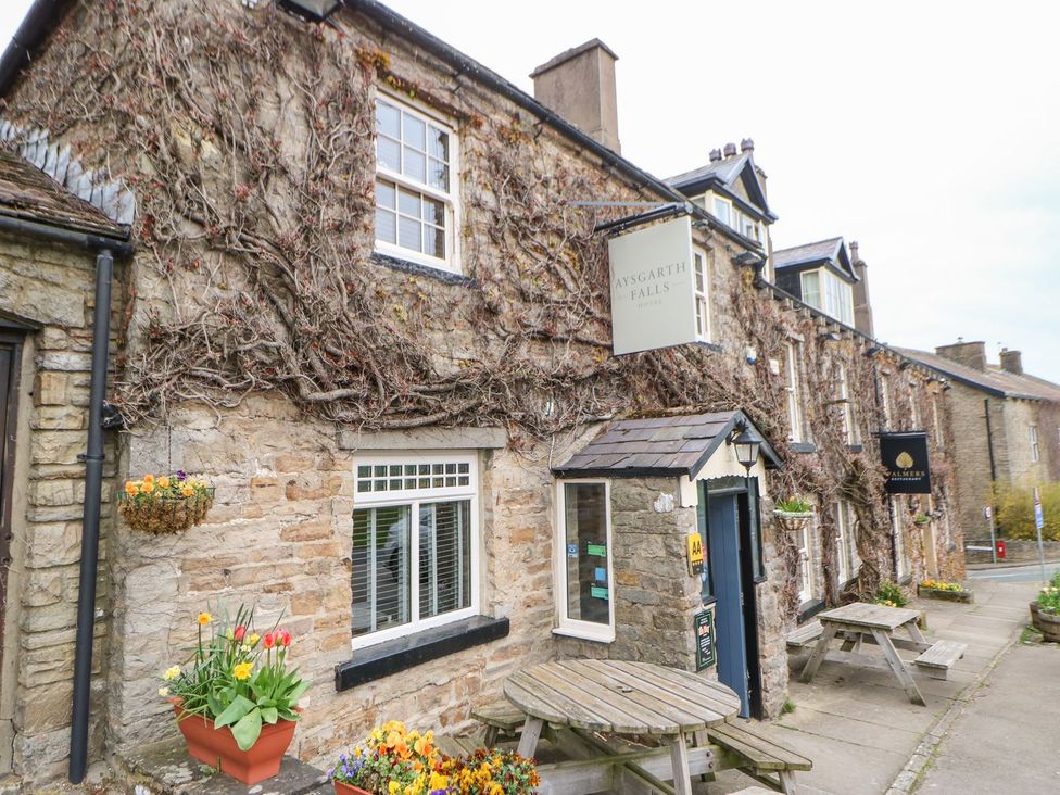 An outdoor area with a stone building and flower pots at Aysgarth Falls in Leyburn