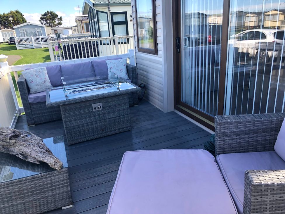 An outdoor seating area with a sofa and coffee table at Sandy beach retreat Prestatyn
