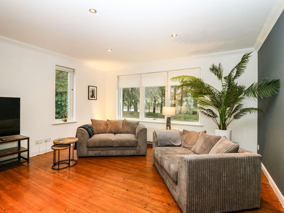 A living room with a sofa, television, and large windows at Boat House in Aberdeen