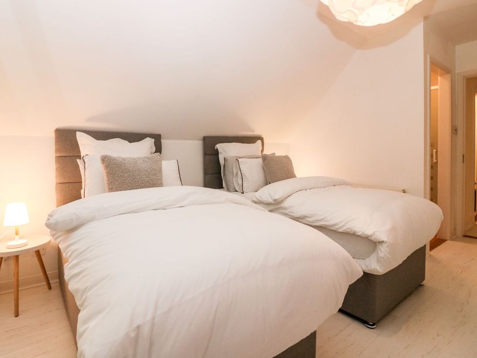 A bedroom with two beds and a bedside lamp at Boat House in Aberdeen