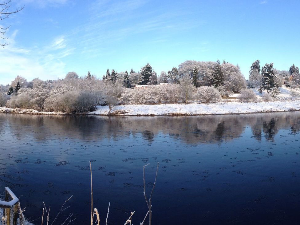 A river bordered by snow-covered trees in Boat House, Aberdeen