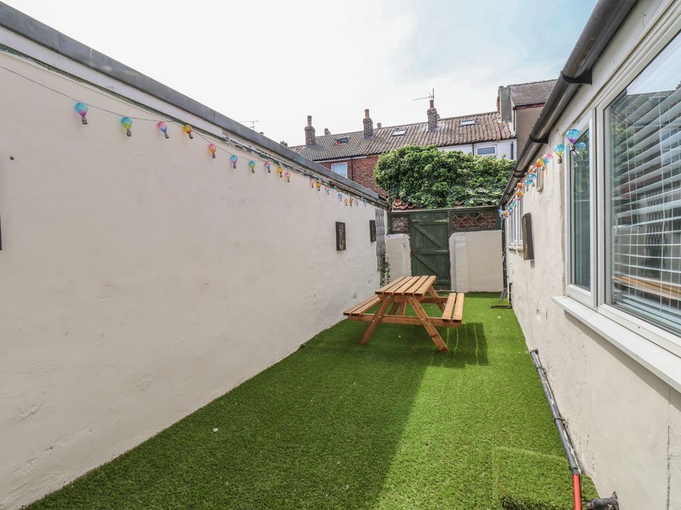 A garden with artificial grass and a wooden table at K & J Holiday House in Bridlington