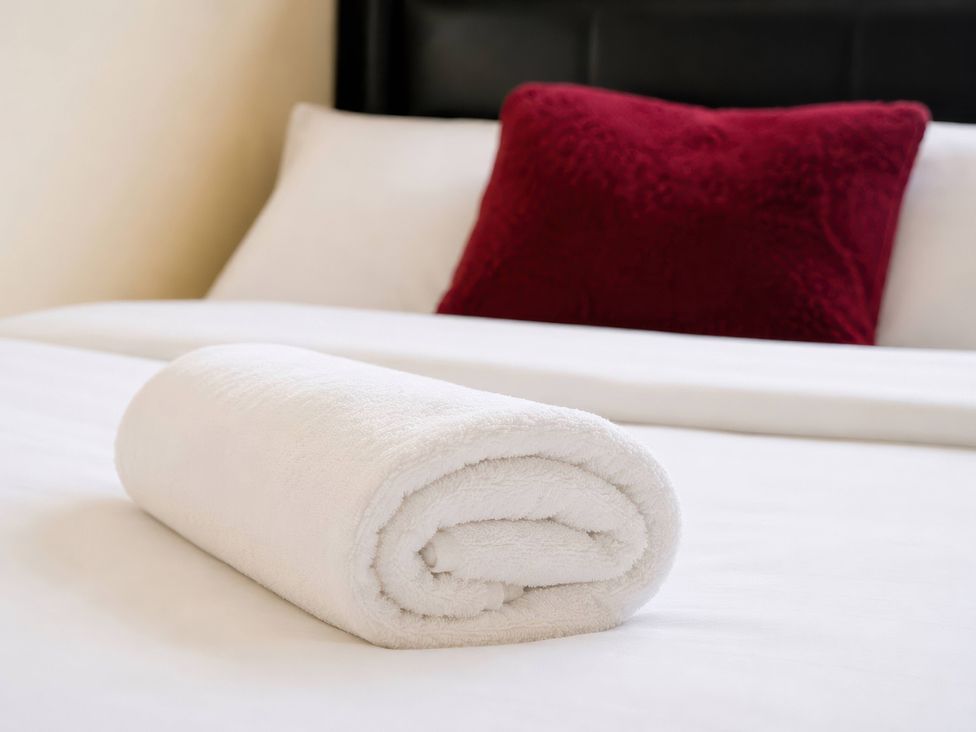 A rolled towel and a pillow on a bed at 4 Britannia Street in Salford