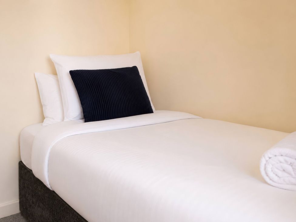 A bed with a black pillow and rolled towel at 4 Britannia Street Salford