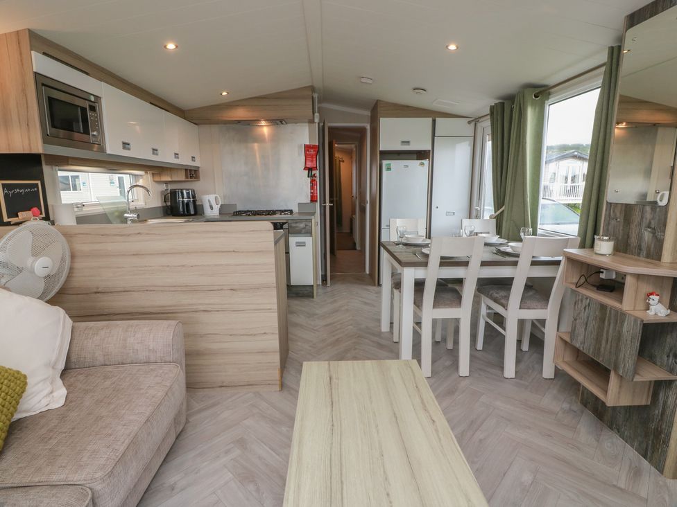 A living room with a sofa and dining area at 101 Bay View in Ayr