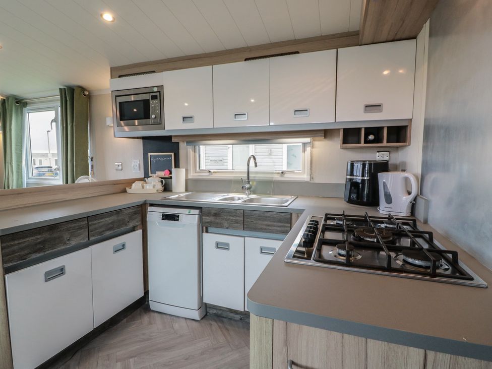 A kitchen with a sink, microwave, and gas stove at 101 Bay View, Ayr