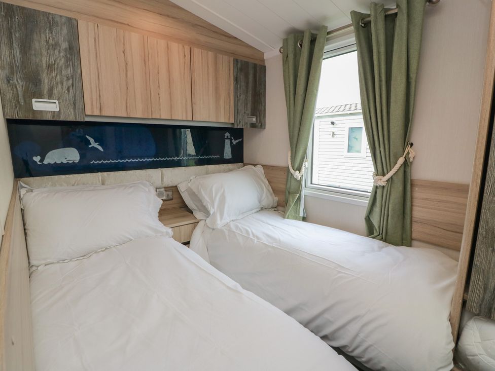 A bedroom with two single beds and a window at 101 Bay View in Ayr