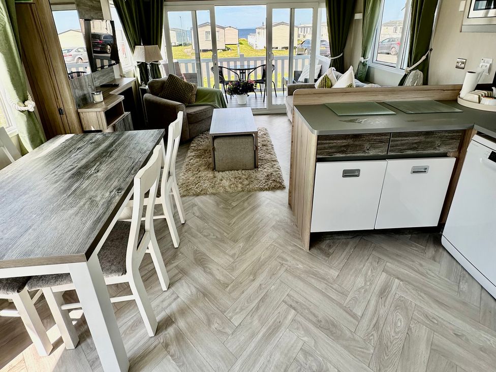 A living room with a dining table and chairs at Craig Tara Holiday Park 101 Bay View in Ayr